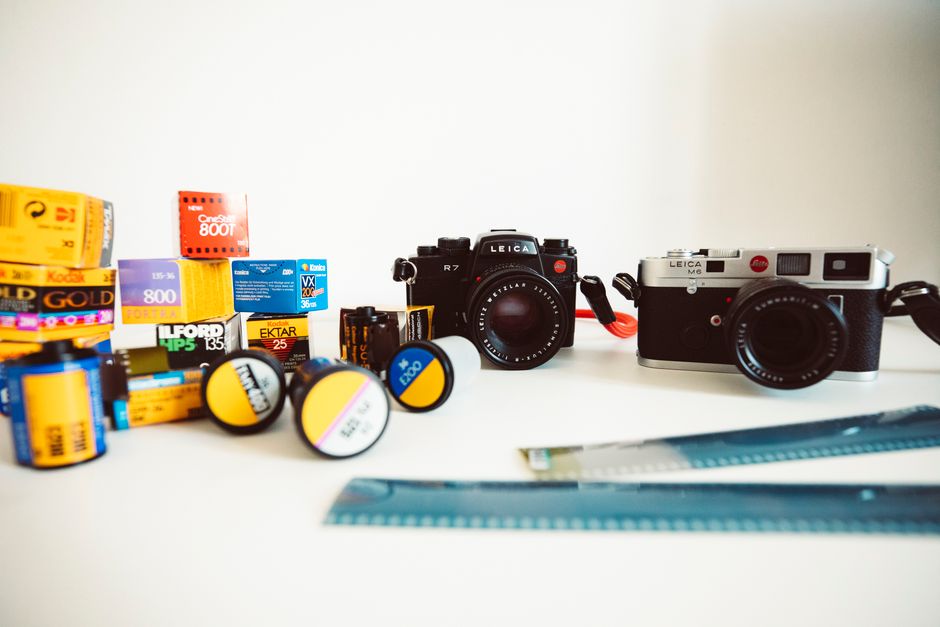 On a white surface inside a property, there are various items related to home relocation and packing, including several rolls of film and photographic paper in different colours and sizes, some in box